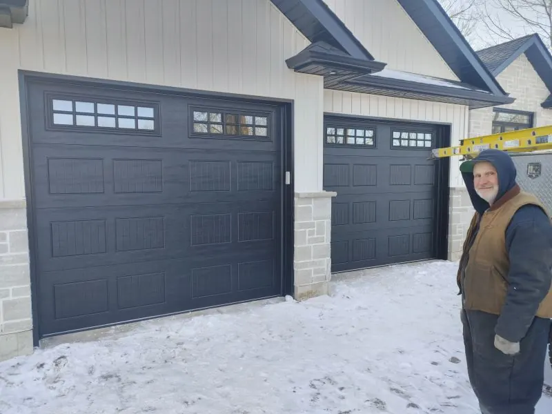 Two black carriage-style garage doors with window inserts