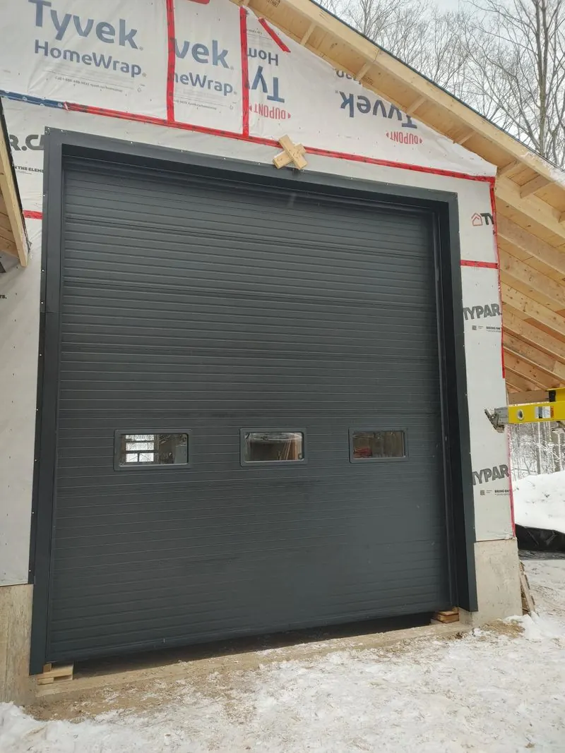 Insulated black commercial overhead door installed during new construction