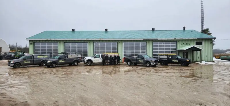 Row of full-view glass overhead doors on a commercial building with Zavtech trucks out front